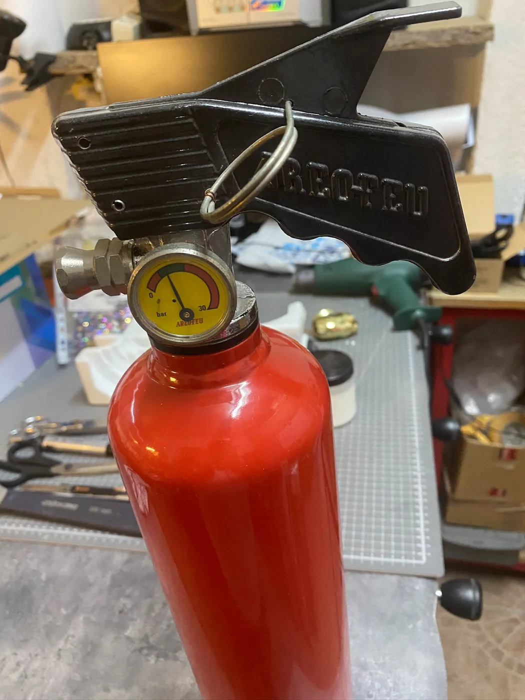 Extincteur rouge d'origine posé sur l'établi de l'atelier avant personnalisation — Art'cade Design Nice