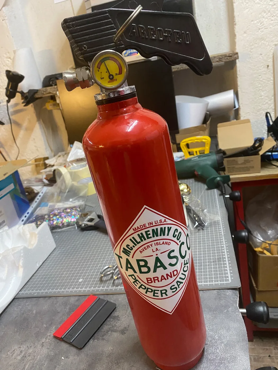 Pose du visuel à la main sur un extincteur en cours de personnalisation à l'atelier — Art'cade Design Nice