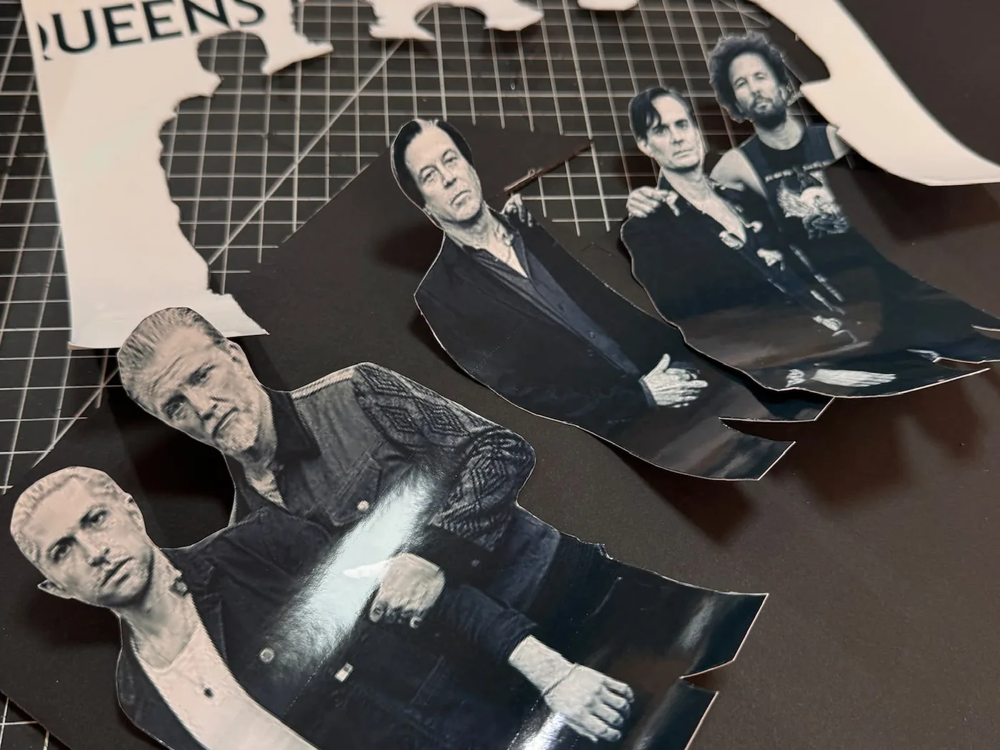Découpe en cours : les silhouettes des membres de Queens of the Stone Age découpées une par une, posées sur un tapis de découpe.